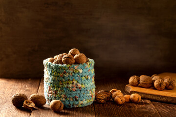 Whole walnuts in wicker basket made of blue fabric on rustic old wooden table