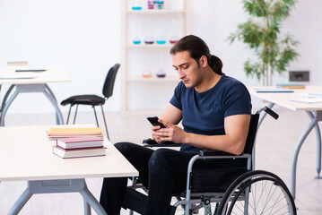 Young male student in wheel-chair preparing for exams