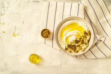 Popular middle eastern appetizer labneh or labaneh, soft white goat milk cheese with olive oil, hyssop or zaatar, over grey table, flaylay.