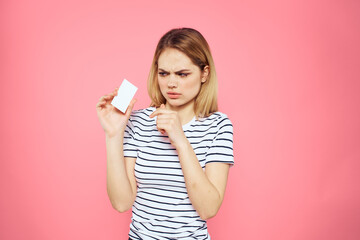 Woman with a business card in her hands a striped T-shirt pink background Copy Space advertising