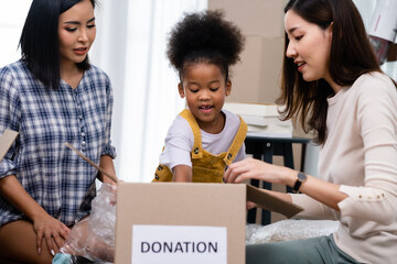 Donation concept. Donate box with clothes, books and toys in family members hand.Happy LGBT family...