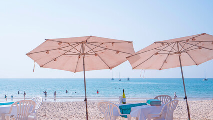 The two umbrellas, tables and chairs with beverage on white sand beach