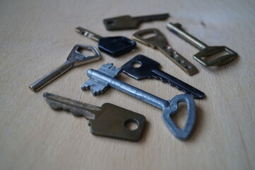 Close-up of old metal keys from locks (doors) on a wooden background. Cold light.