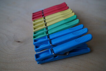 Close-up (macro) of clothes pegs in different colors on a wooden background