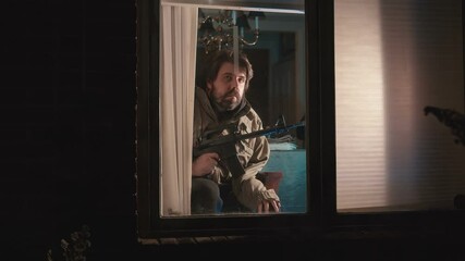 crazy guy watching out window with gun