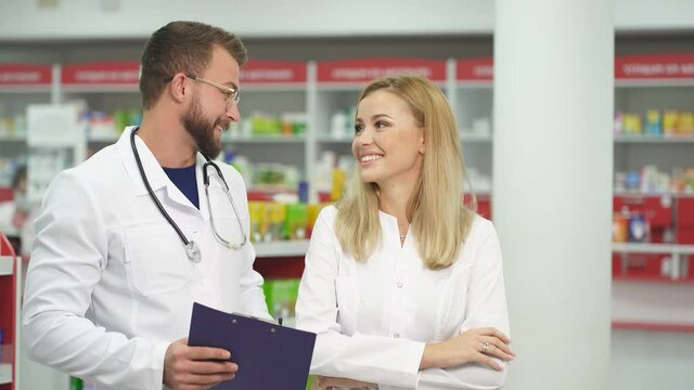 Portrait of two beautiful pharmacist in uniform at modern drugstore.