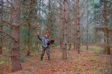 Forest engineer works in the autumn forest with a computer. Forest worker performs forest...