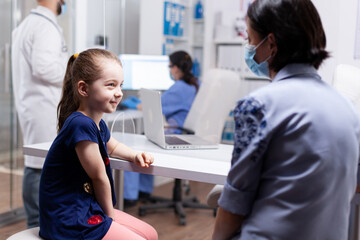 Mother and daughter at doctor appointment during coronavirus pandemic. Specialist in medicine providing health care services consultation, radiographic treatment in clinic.
