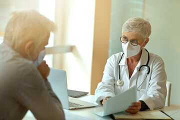 Doctor with face mask listening to patient in office, 19-ncov pandemic