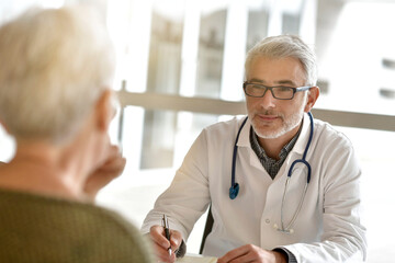 Fototapeta premium Mature practitioner in office listening to patient