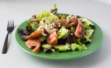 vegetable salad of greens, tomatoes and cucumbers on a green plate