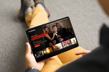 Man looking TV series and movies via streaming service on his digital tablet