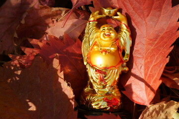 Hotei figure on the background of autumn leaves. Symbol of happiness and well-being.