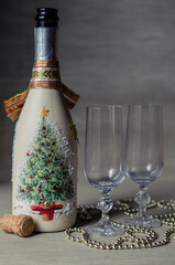 Decorative bottle with champagne, two glasses, decoration on a light background close-up
