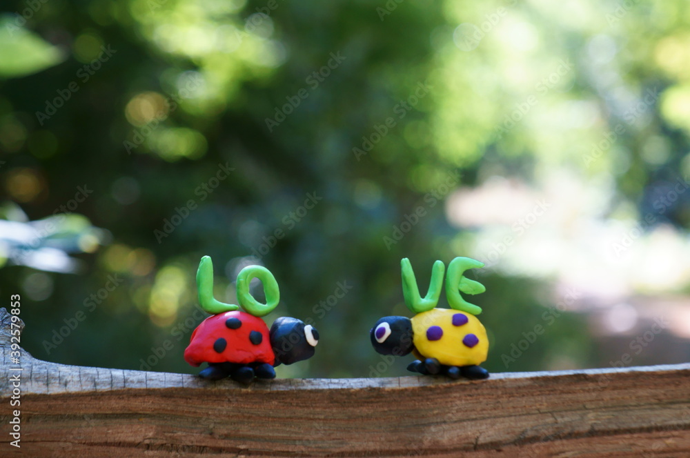 Poster Two ladybugs made of plasticine on a colored background. Next to it is the inscription love.