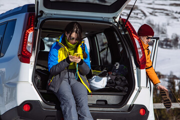 woman sitting in suv car trunk full of ski and snowboard stuff