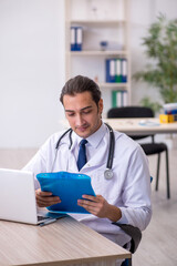 Young male doctor taking notes at the hospital