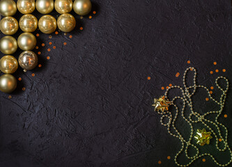 Gold glass balls, decorations on a black background. Christmas decor. Place for signature.