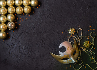 Gold glass balls, carnival mask, decorations on a black background. Christmas decor. Place for signature.