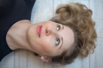 Close-up portrait of a young beautiful blonde woman lying on the wooden floor.