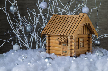 Mock-up of a wooden house in artificial snow on a background of white branches with glass balls. Christmas decor.