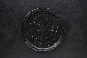 Empty black ceramics plate and on dark background.