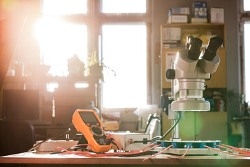 Modern microscope, connectors component and large green microcircuit in workshop laboratory