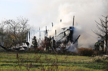 Fototapeta premium Firefighters extinguish a burning country house.