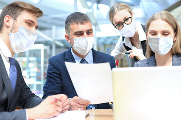 Fototapeta na wymiar Image of business partners wear preventive masks discussing documents and ideas at meeting.