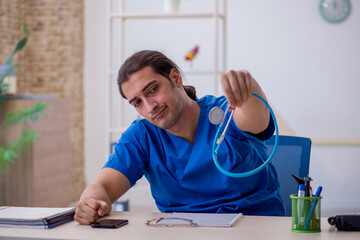 Naklejka premium Young male doctor being extremely tired in the clinic