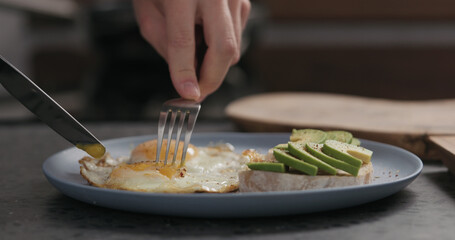 Slow motion man cut fried egg on blue plate