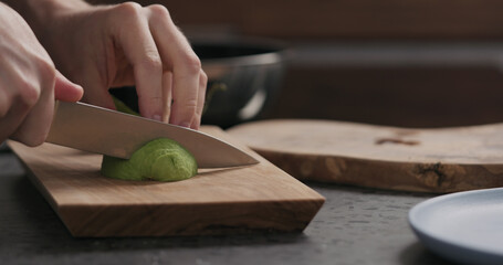 Slow motion man slicing avocado on olive wood board