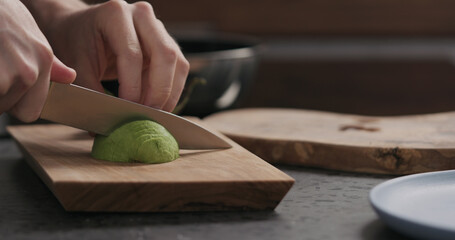 Slow motion man slicing avocado on olive wood board