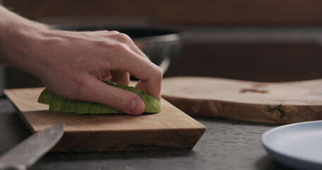 Slow motion man slicing avocado on olive wood board
