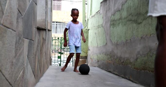 Father kicking ball to son, African dand and child playing soccer together