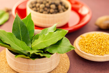 a dried aromatic bay leaves in wooden bowl among spices, mediterranean condiment close up