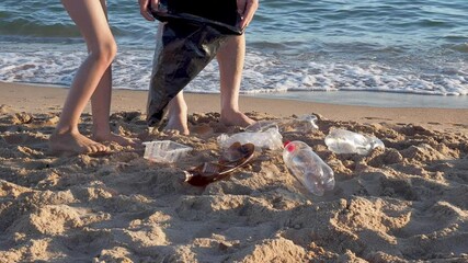 Dad and son collect plastic bottles from the black sea. Paradise beach pollution. Problem scattered rubbish trash garbage on the beach sand caused by man-made pollution and environmental