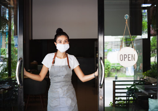 Happy Thai waitress with protective face mask, standing  doorway,  restaurant reopening, Thailand, Koh Phangan
