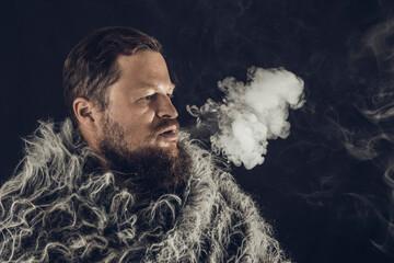 Solid bearded man dressed in a fur mantle exhaling vapour