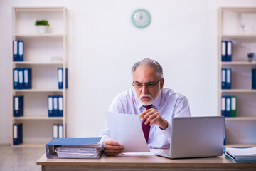 Old male employee working in the office