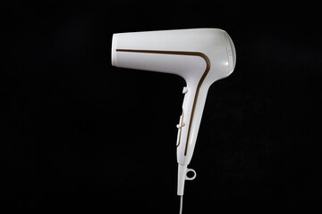 Professional stylish hairdryer isolated over a black background. White Ionic Hair Dryer with Hair Care Tool. Modern Blow Dryer.