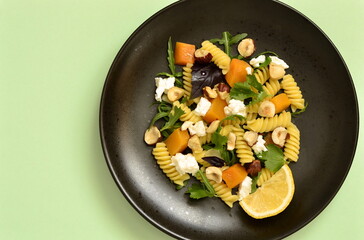 Pasta with baked pumpkin, feta, herbs and hazelnuts, top view, copy space