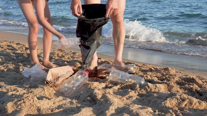 Dad and son collect plastic bottles from the black sea. Paradise beach pollution. Problem scattered rubbish trash garbage on the beach sand caused by man-made pollution and environmental