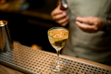 wine glass with drink decorated with slice of cucumber stands on bar counter surface