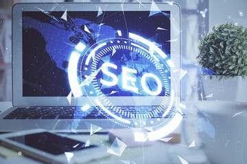 Double exposure of table with computer and seo drawing hologram. Search optimization concept.