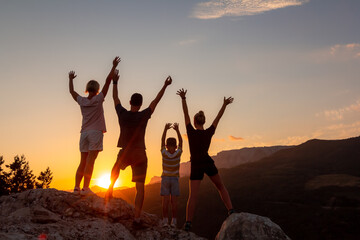 Happy family in mountain. Mother, father, children son and daughter with arms raised on nature on sunset