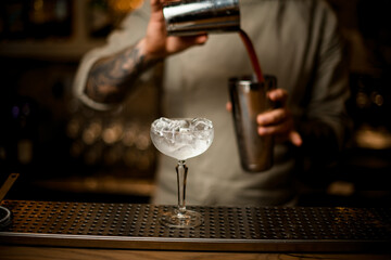 wine glass full of ice cubes stands on the bar counter.