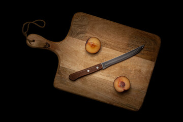 Nutrition concept. Cut plum and knife in the form of percent on a wooden board, black background. Flatlay photo.