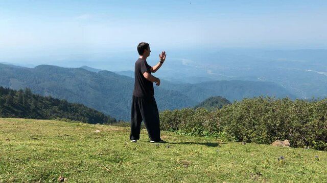 Male Practice Tai Chi with a Mountain View. Man Doing Meditation Practice Alone in a Peaceful Place.