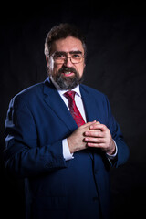 Mature businessman dressed in blue suit with red tie studio portrait.